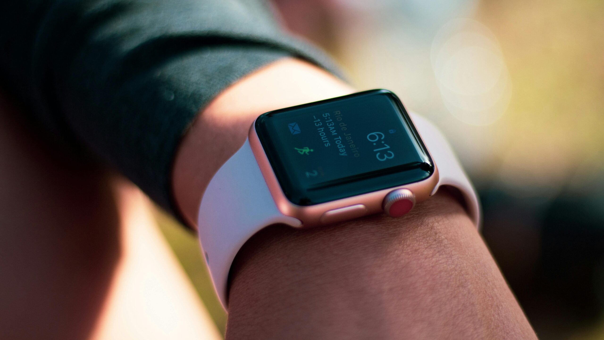 Smartwatch with digital screen displaying 6:13, worn on wrist outdoors.